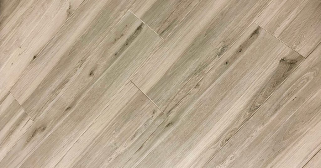Close-up diagonal view of several luxury vinyl floor planks in a light grey oak color laid on someone’s floors.