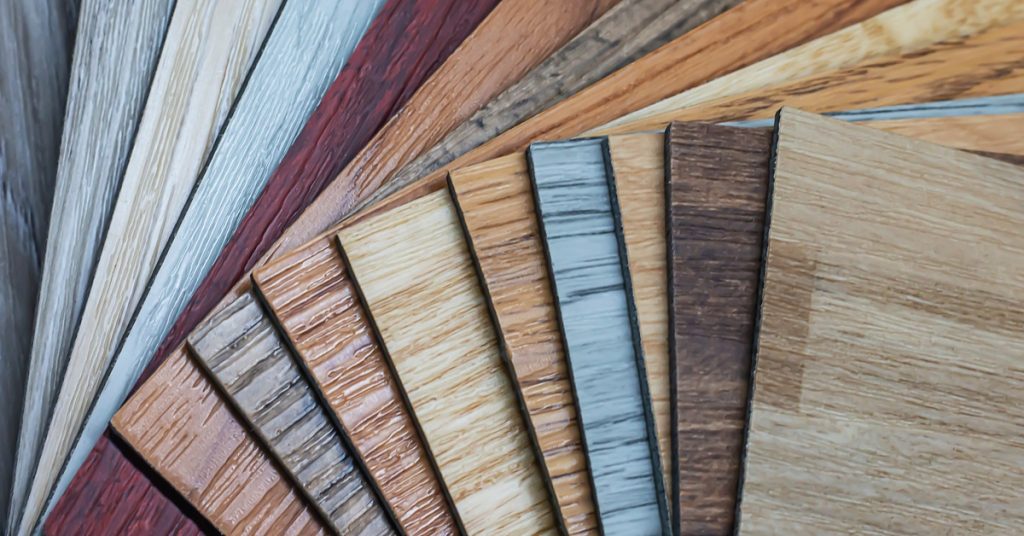 Close-up of fifteen different PVC vinyl flooring planks in various different styles and shades from reds to greys.