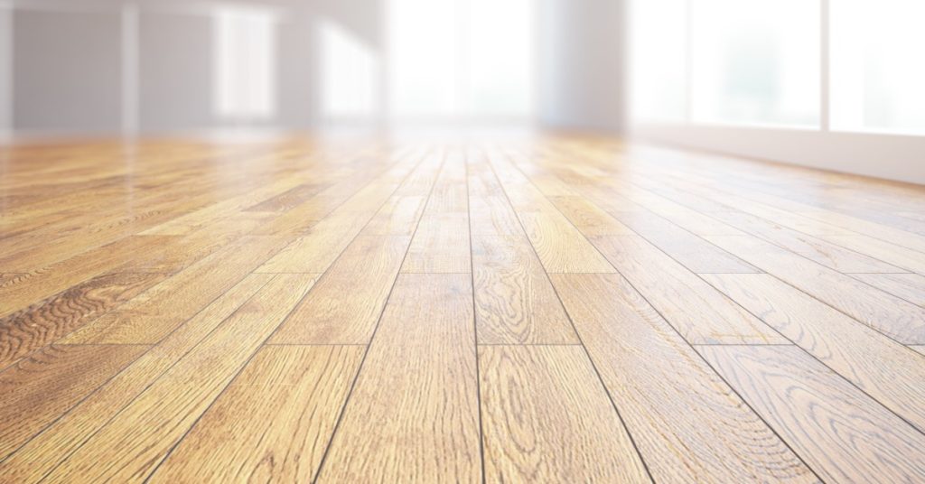 Sun shining through the windows onto the hardwood floor inside a residential space. The wooden planks are thin.